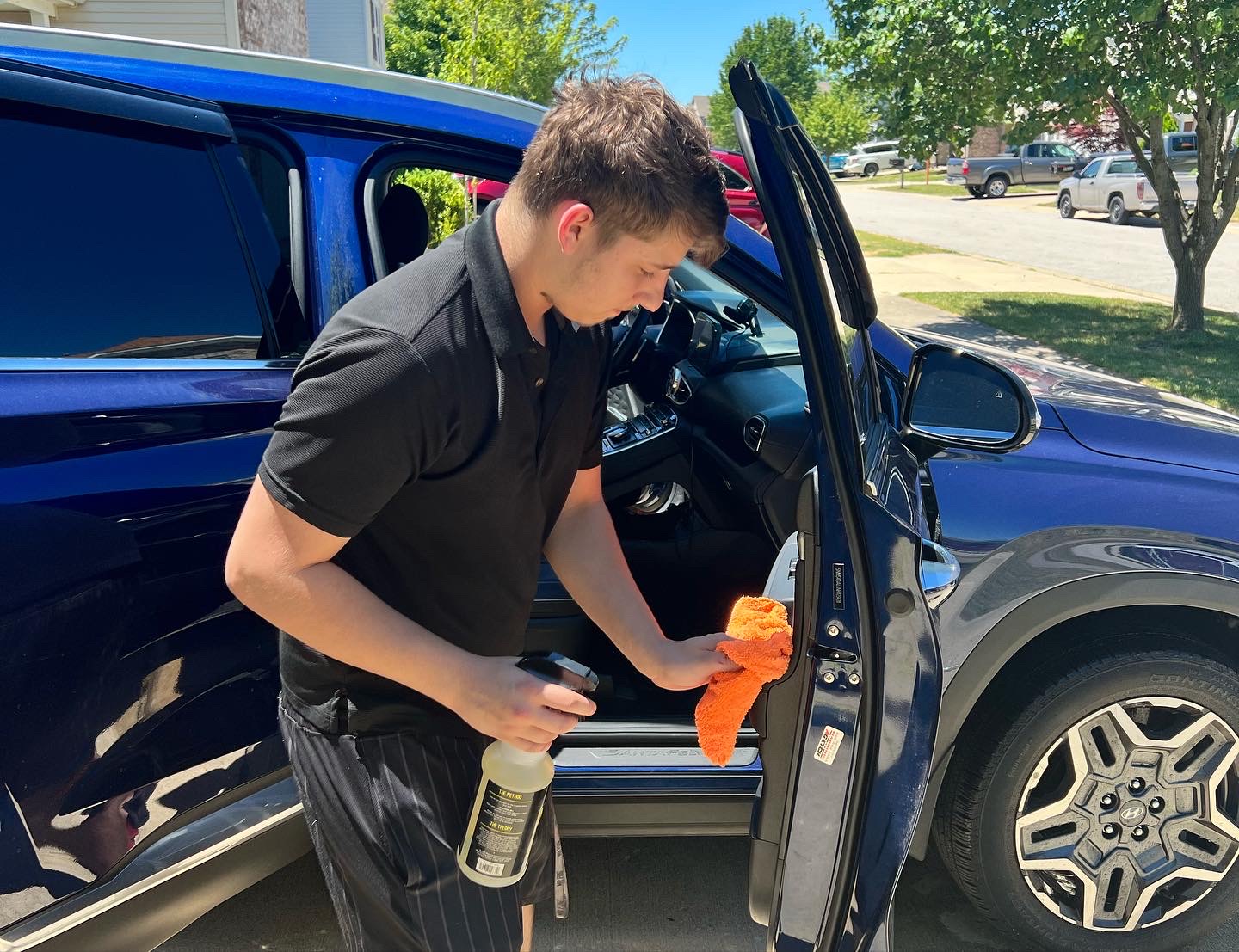 Detailer cleaning door jamb on blue SUV — precision automotive detailing